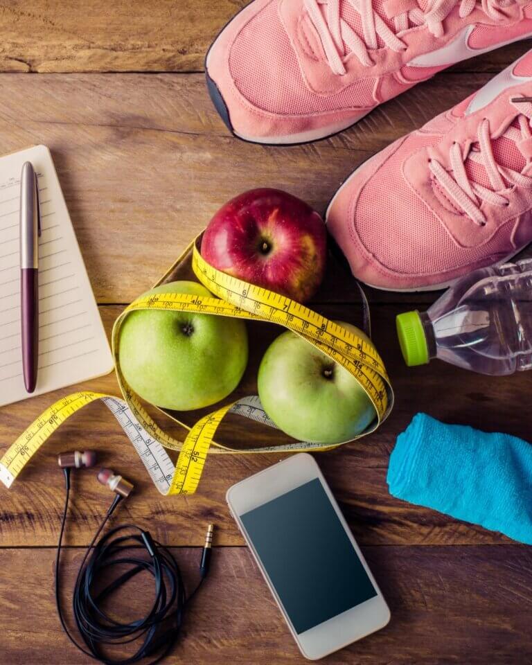Sportschoenen, appels, meetlint en waterfles bij sport en gewichtsverlies